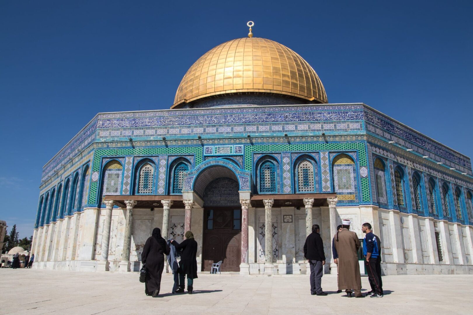 few people standing in front of a mosque