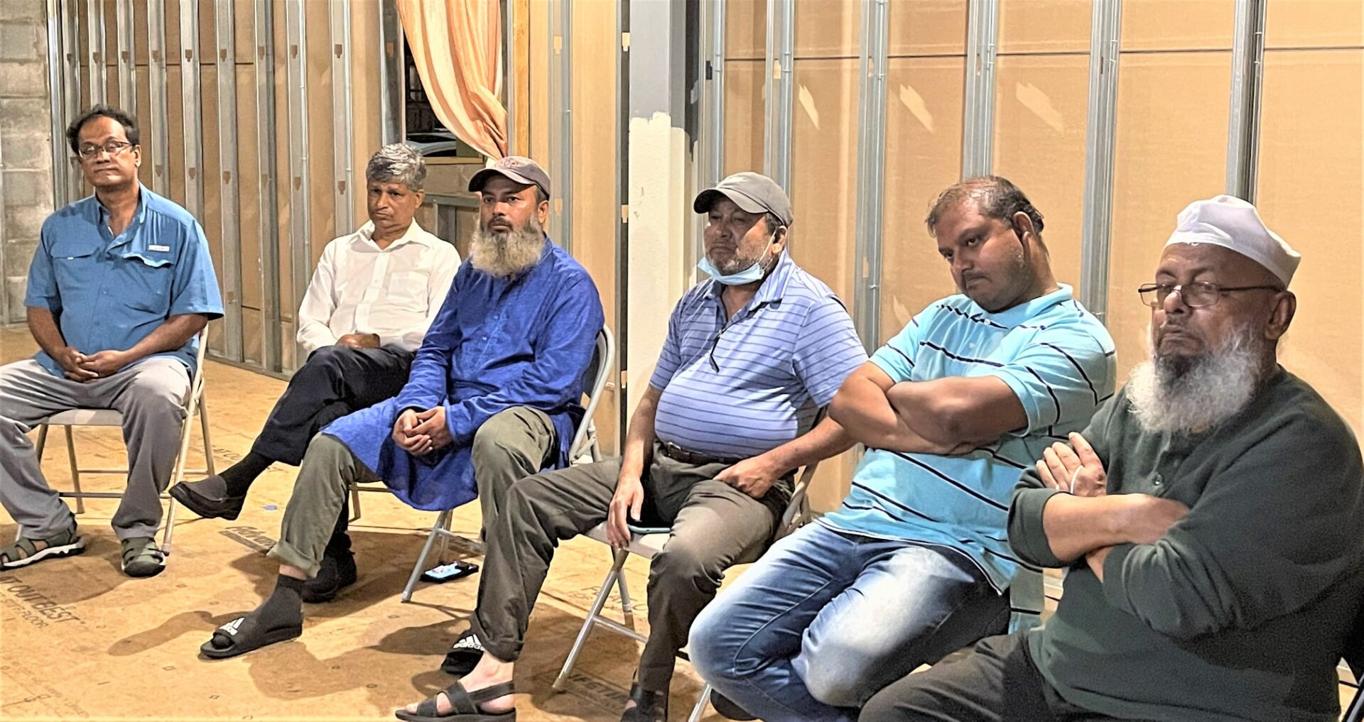 Six men sitting on foldable chairs